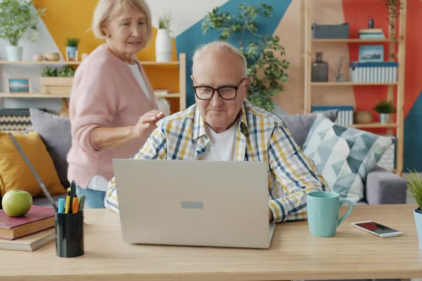 An older couple at home planning together at a laptop