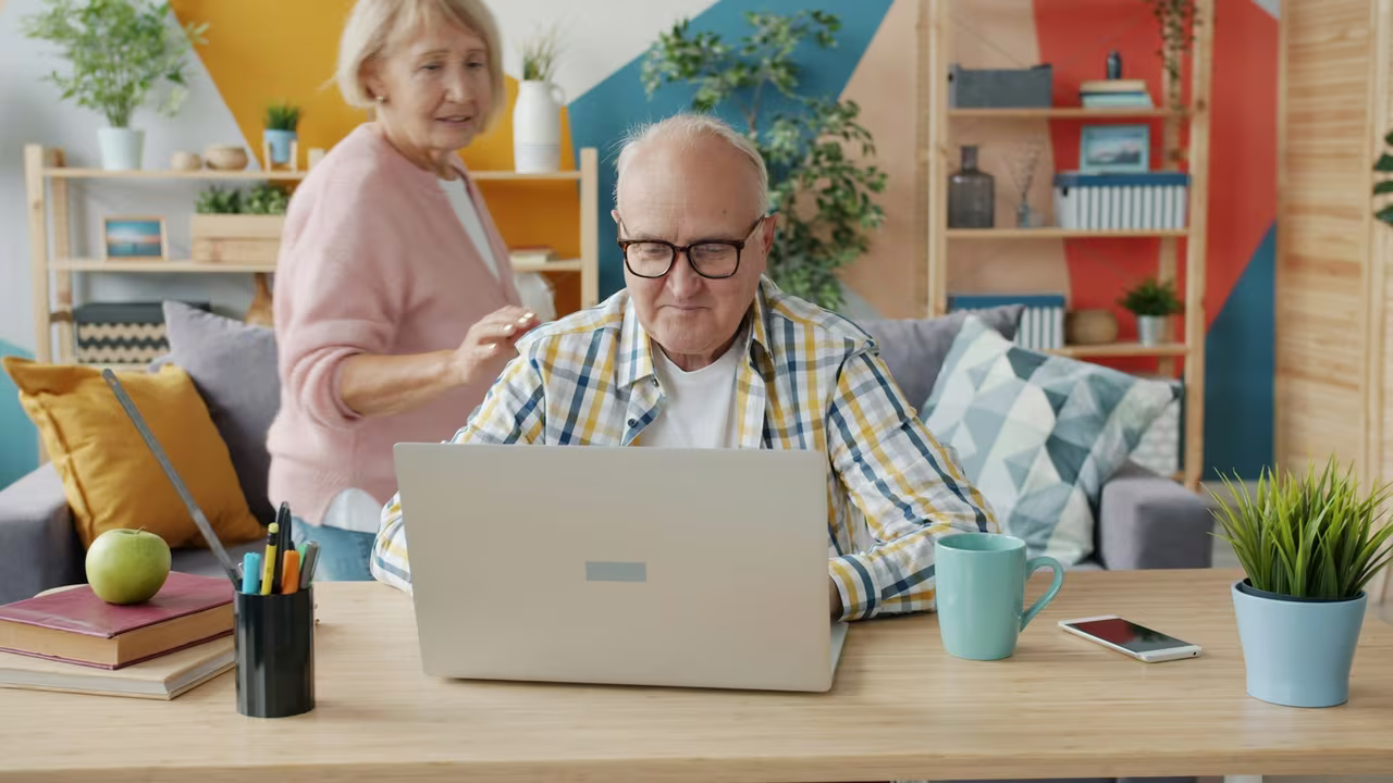 An older couple at home planning together at a laptop